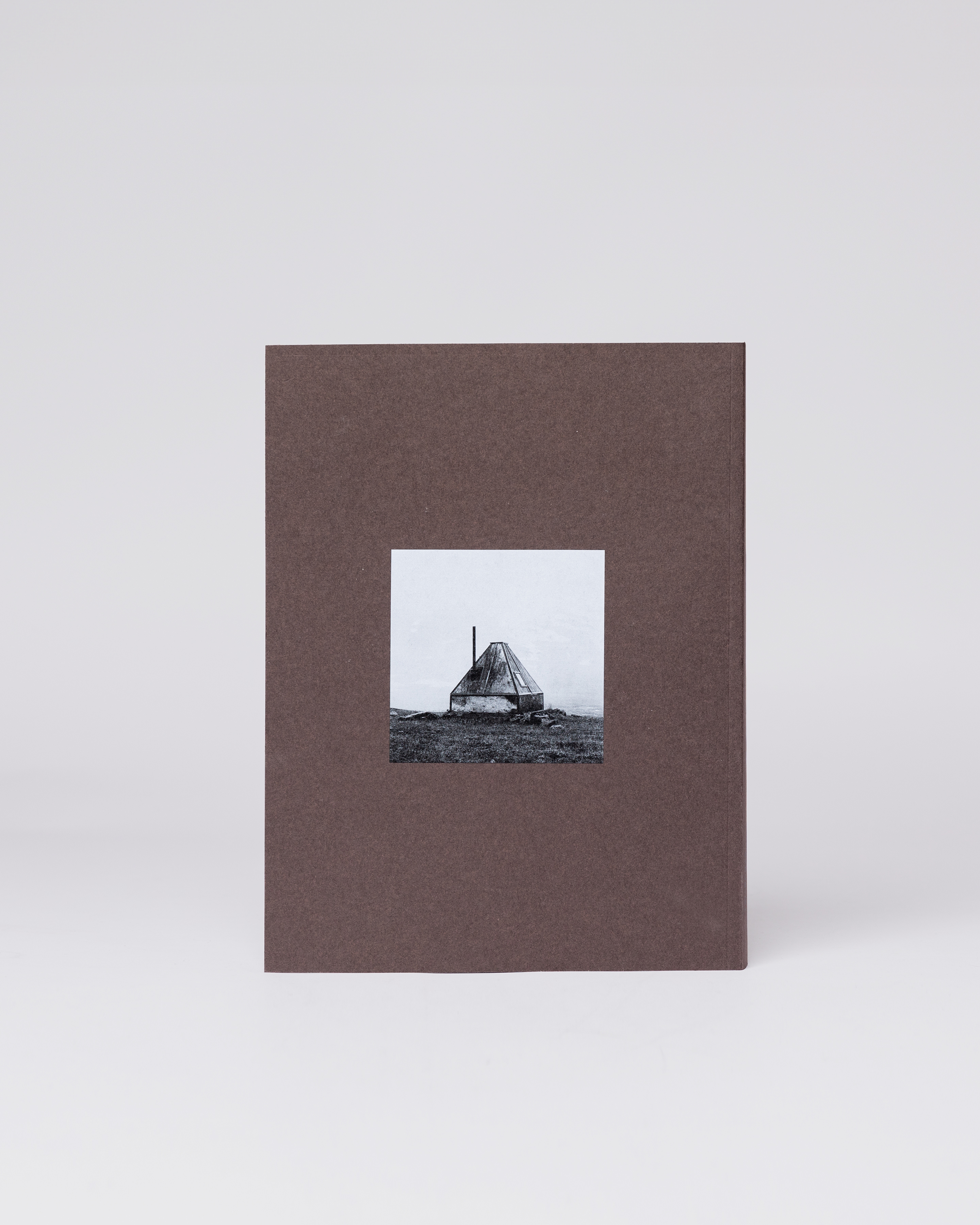 A brown book with a photo in the middle. Backside view showing the book Sandqvist 20 years of nordic landscapes.