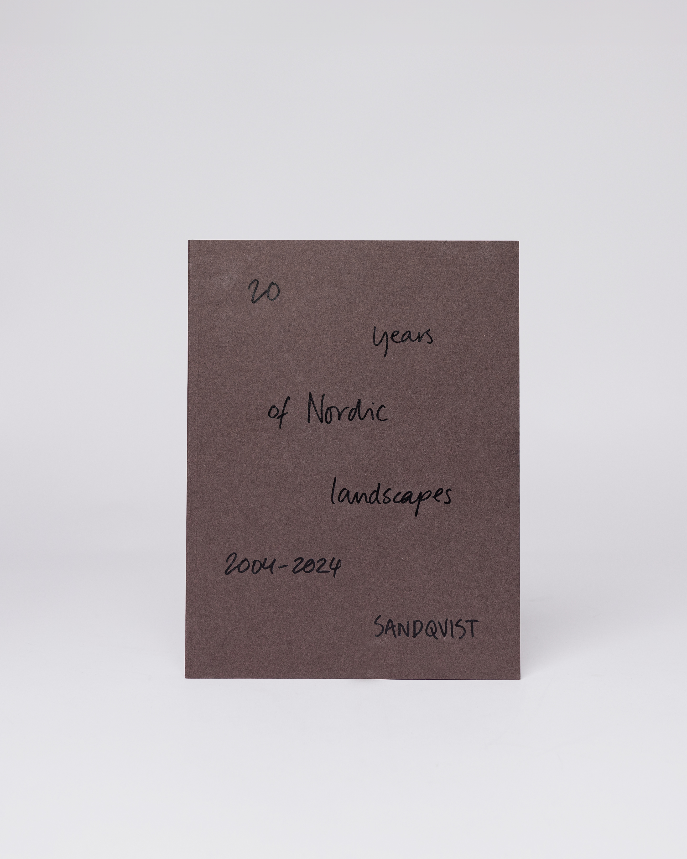 A brown book with the text "20 years of nordic landscapes". Front view showing the book Sandqvist 20 years of nordic landscapes..