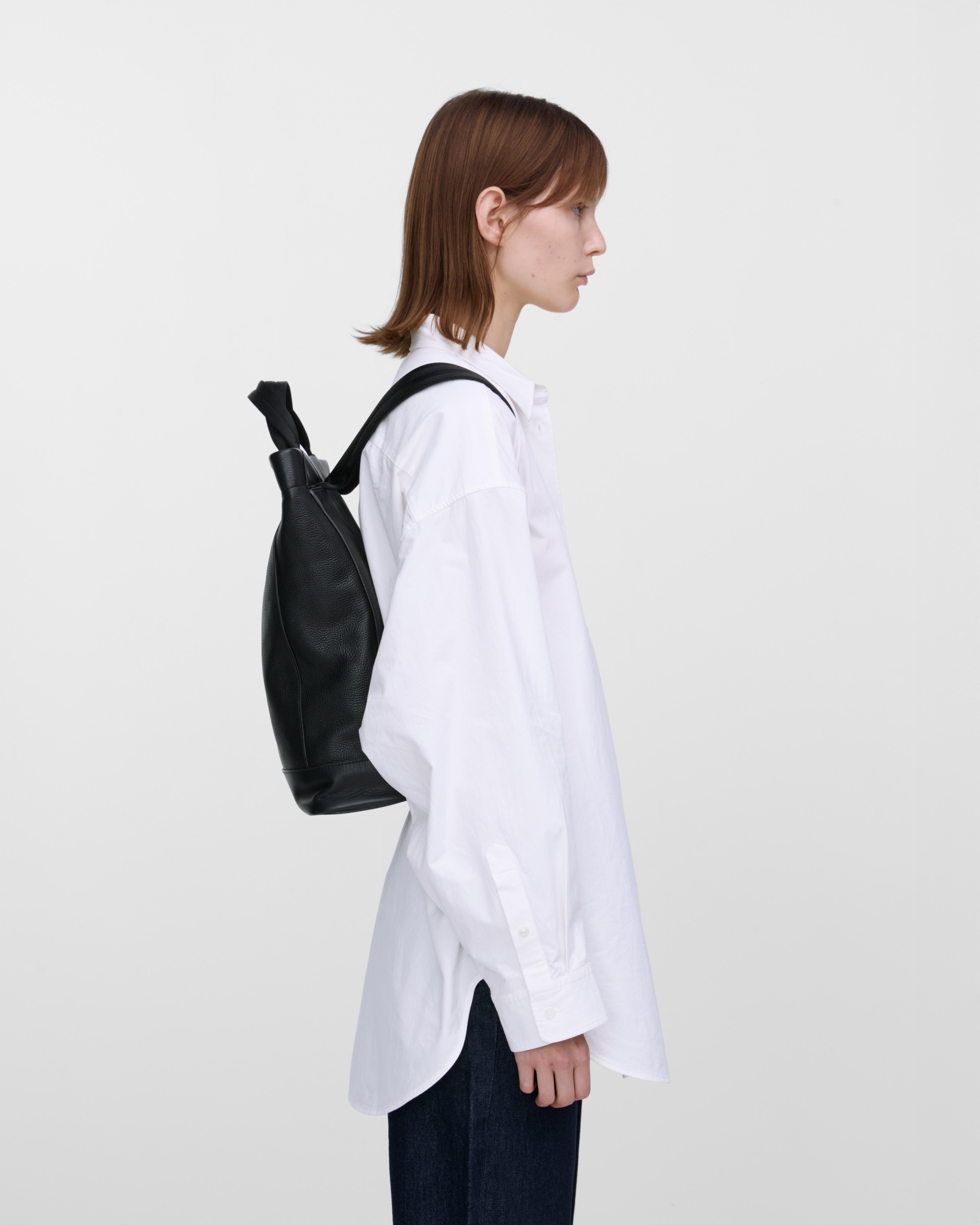 Female model carrying backpack Sandqvist LEATHER Tote Backpack, side view showing fit and size. 