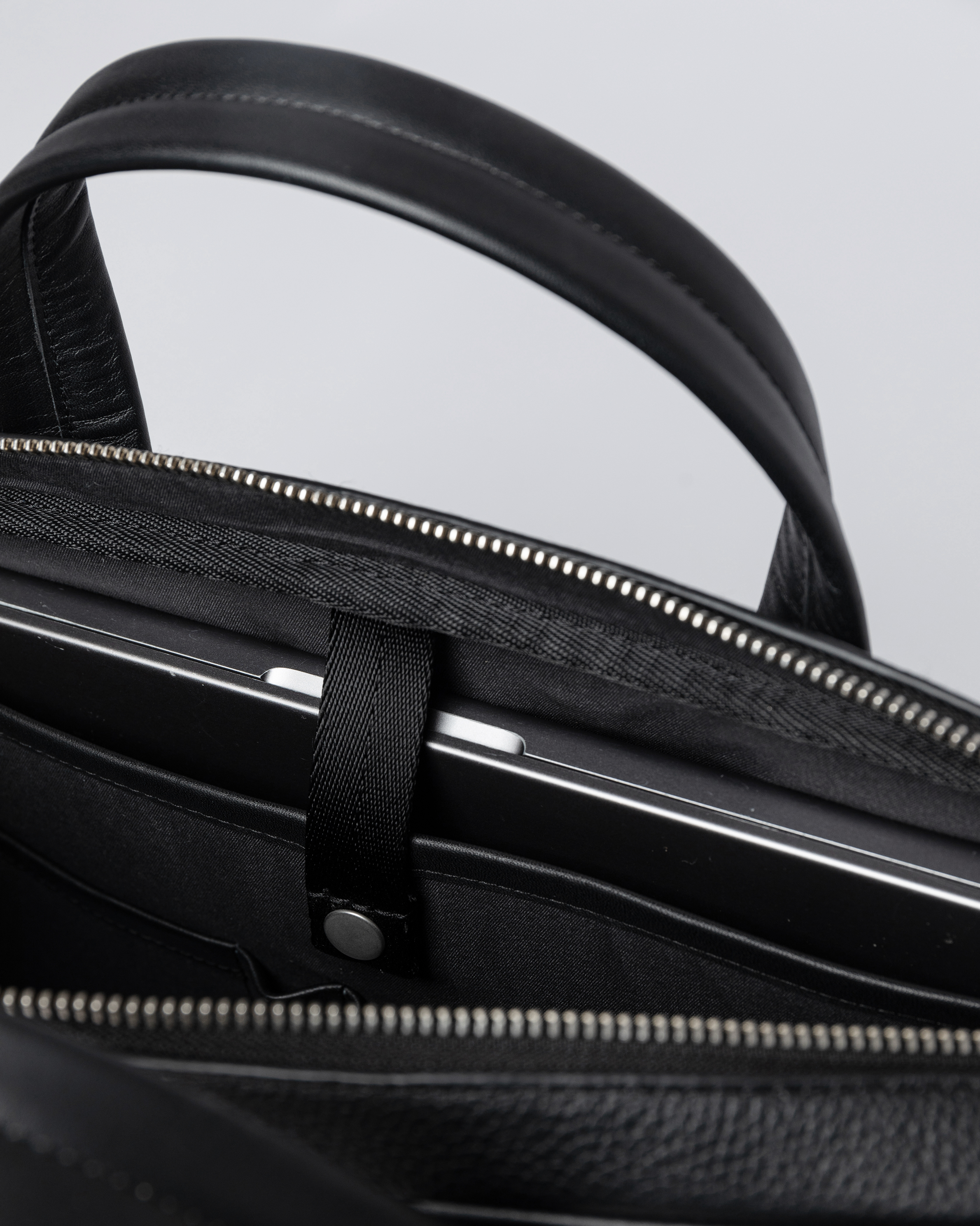 Internal laptop pocket with strap and press button in the Sandqvist LEATHER Briefcase black.