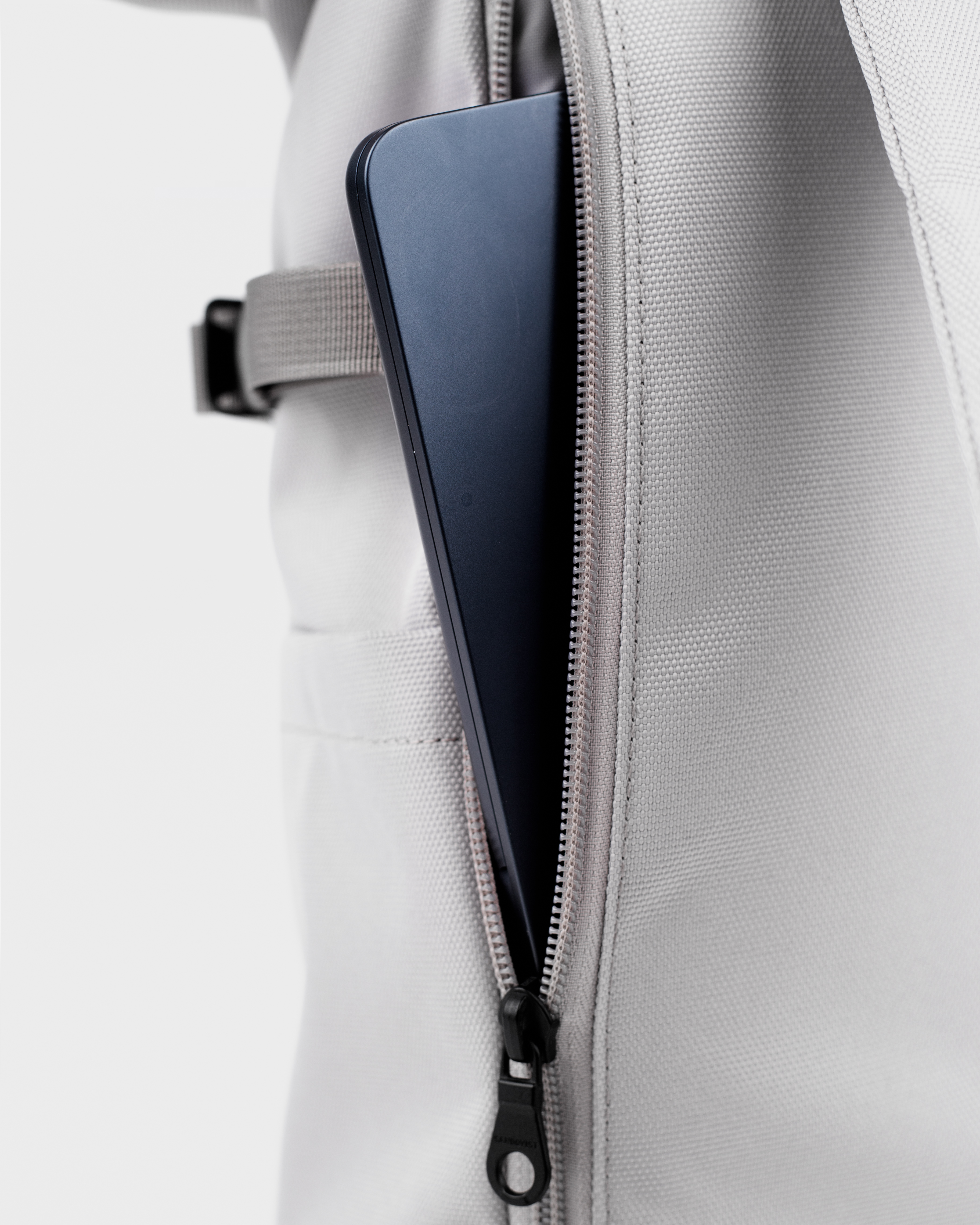 Sandqvist Icon Rolltop Backpack L 16, grey. Close-up of the outside laptop compartment with a zipper.