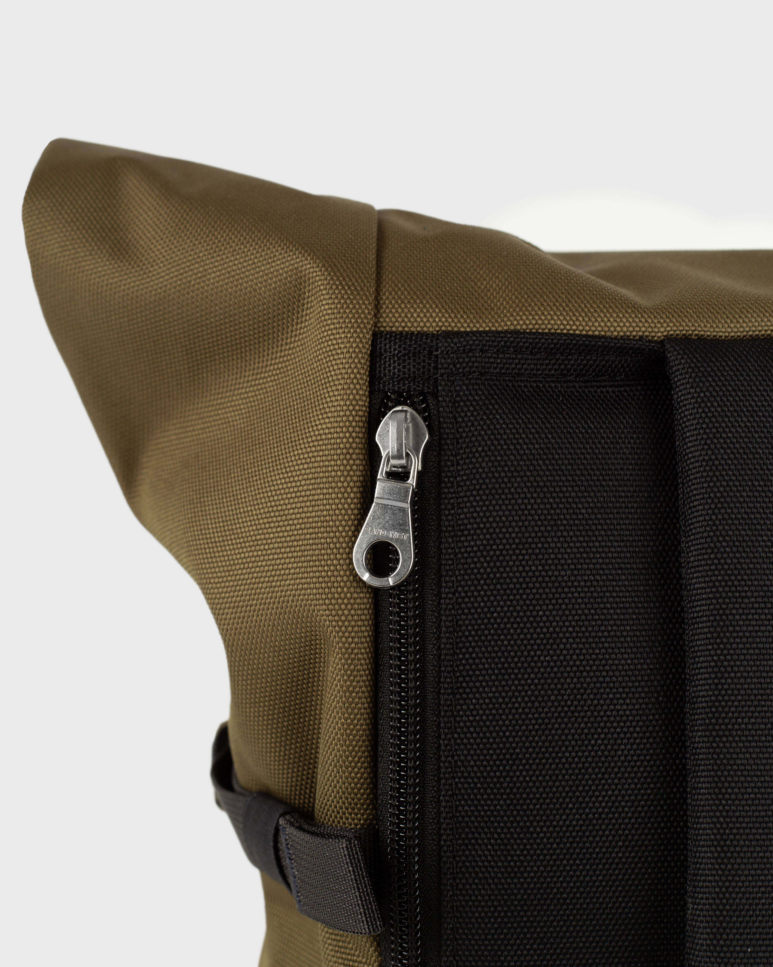 Sandqvist Icon Rolltop Backpack L 16, green and black. Close-up of the laptop compartment zipper.