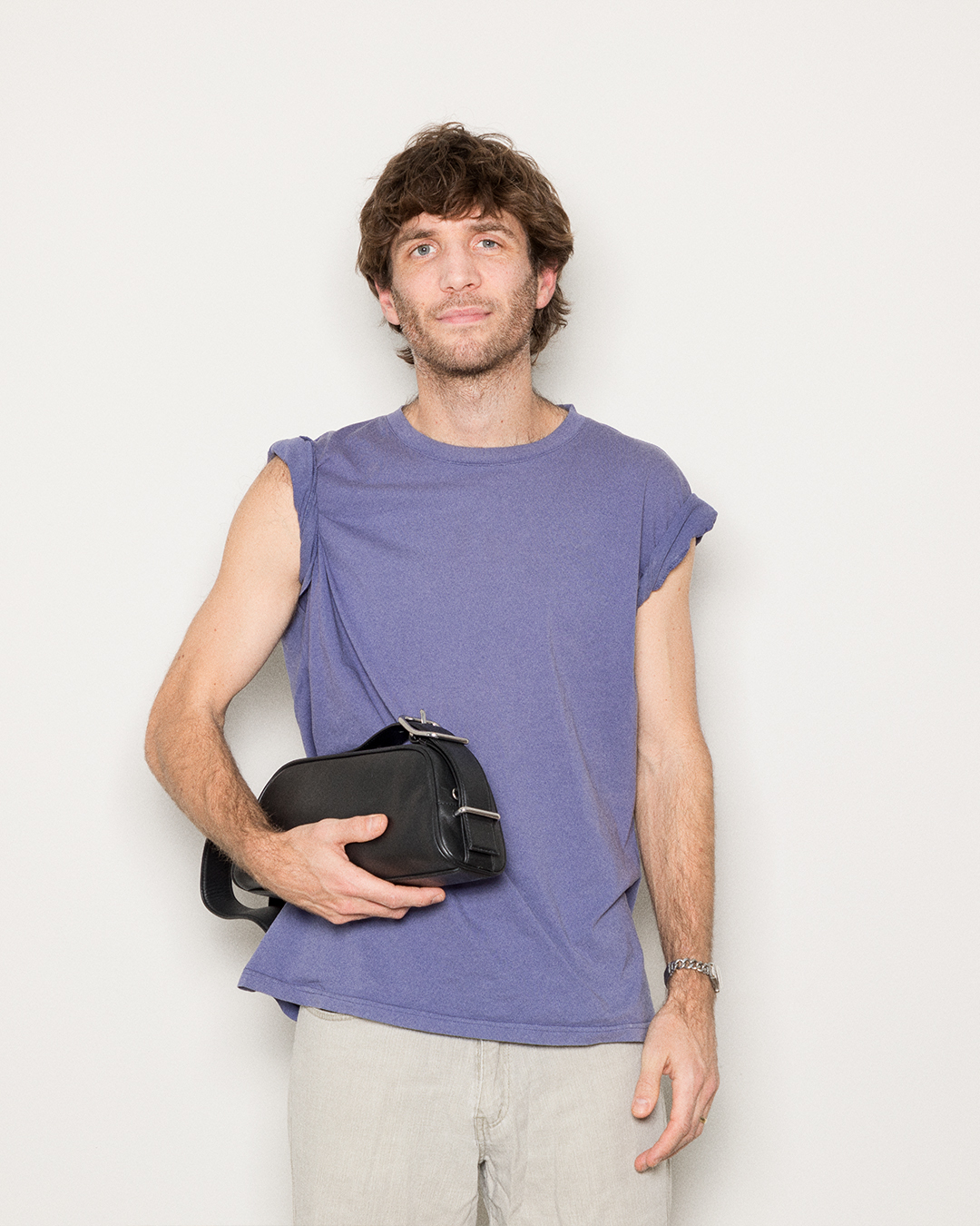 Manlig modell som håller Sandqvist Leather Baguette Bag, svart. Framifrån, håller väskan som en clutch.