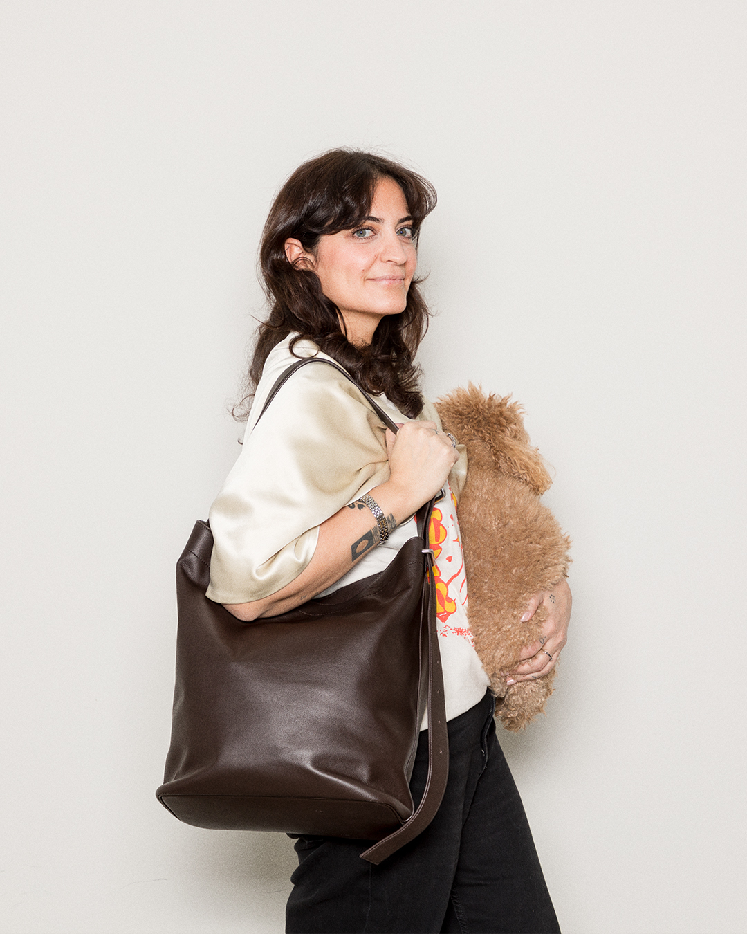 Female model wearing the Sandqvist Leather Shopper Bag, dark brown while holding a dog.