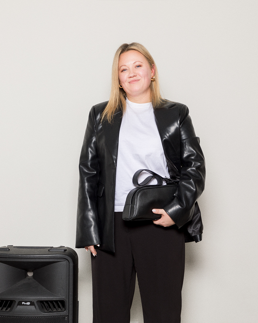 Kvinnlig modell håller i en svart läderväska av typen Baguette Bag. Framifrån med synligt handtag.