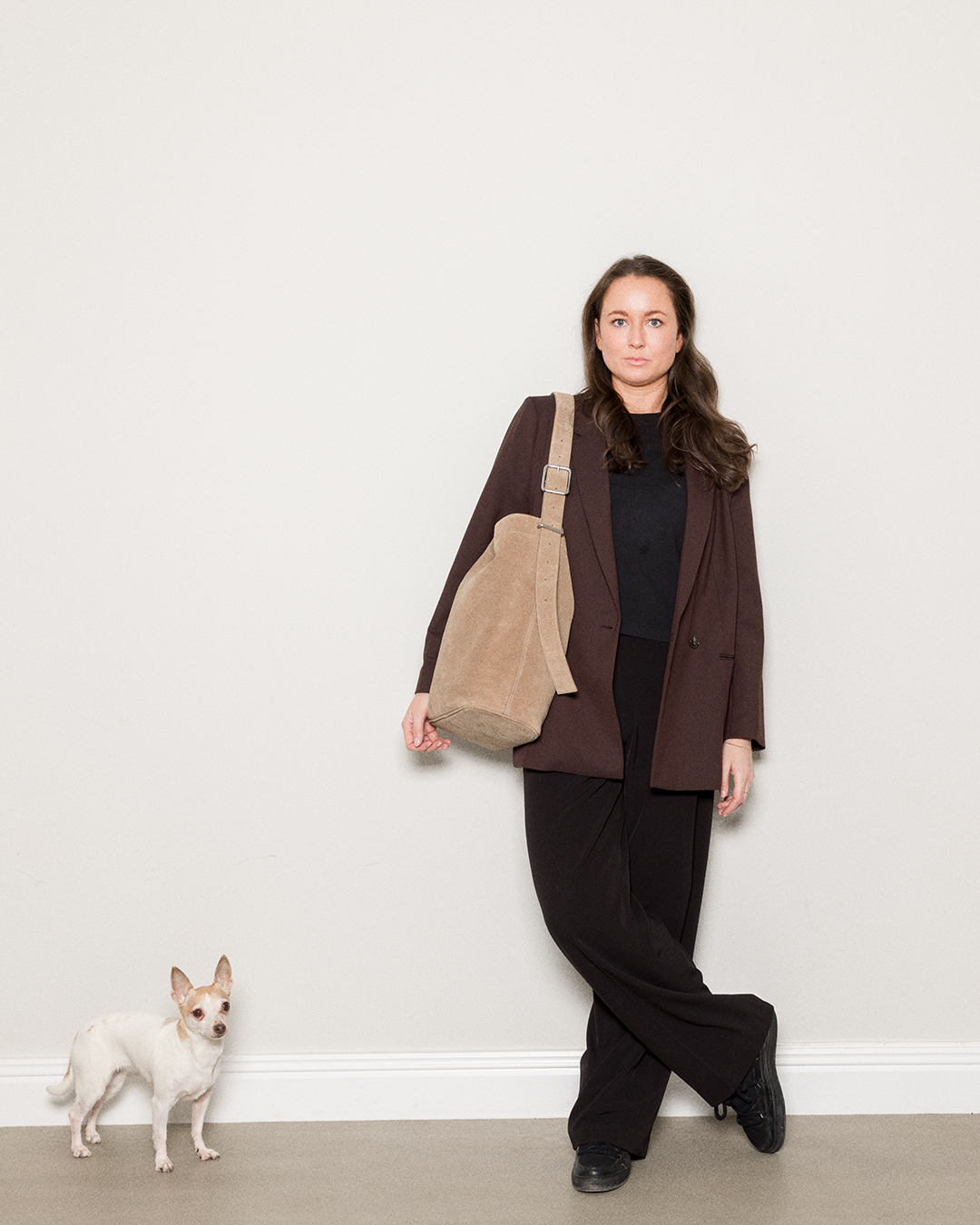 Kvinnlig modell som står bredvid en hund, hon bär Sandqvist Suede Shopper Bag, taupe. Framifrån, bär väskan på ena axeln.