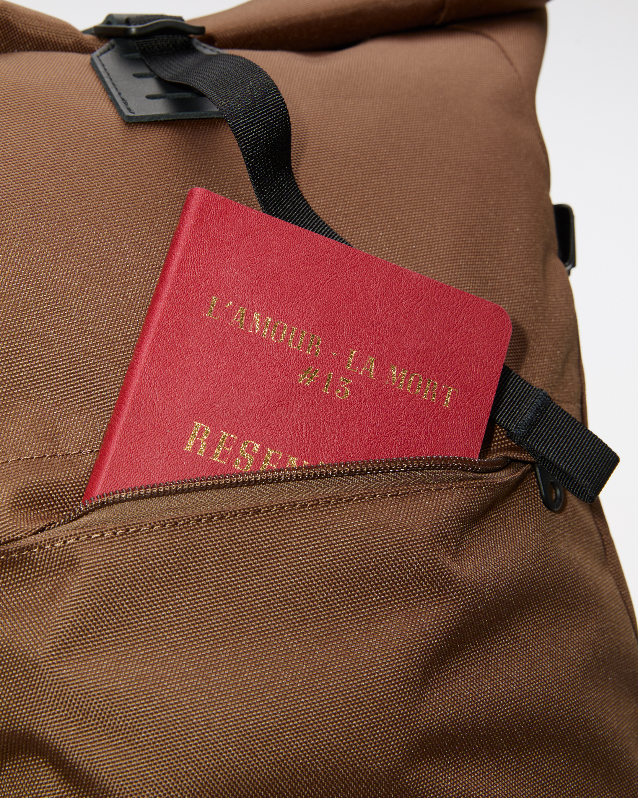 Rucksack, Sandqvist ICON Rolltop Backpack 16”, brown. Nahaufnahme der Vordertasche, aus der ein Buch herausragt.