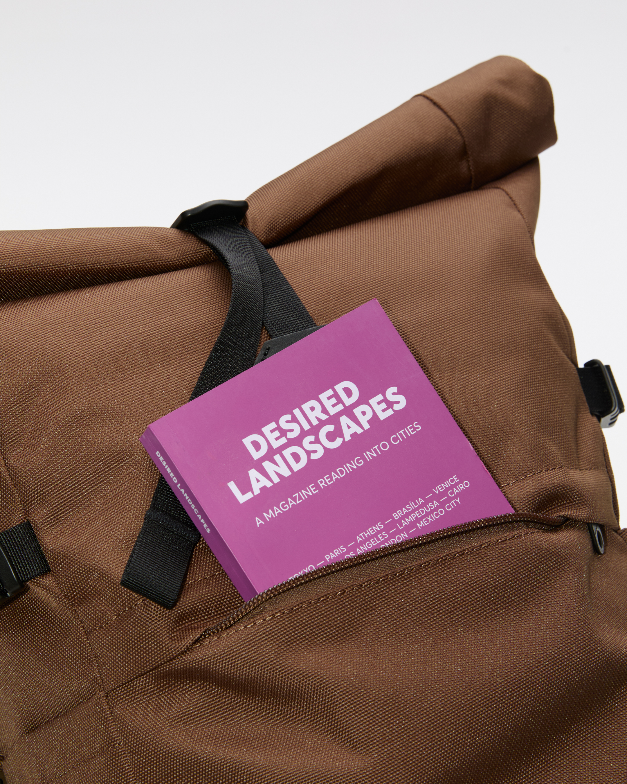 Sandqvist ICON Rolltop Backpack 14”, brown. Close-up of the front pocket with a book sticking out.
