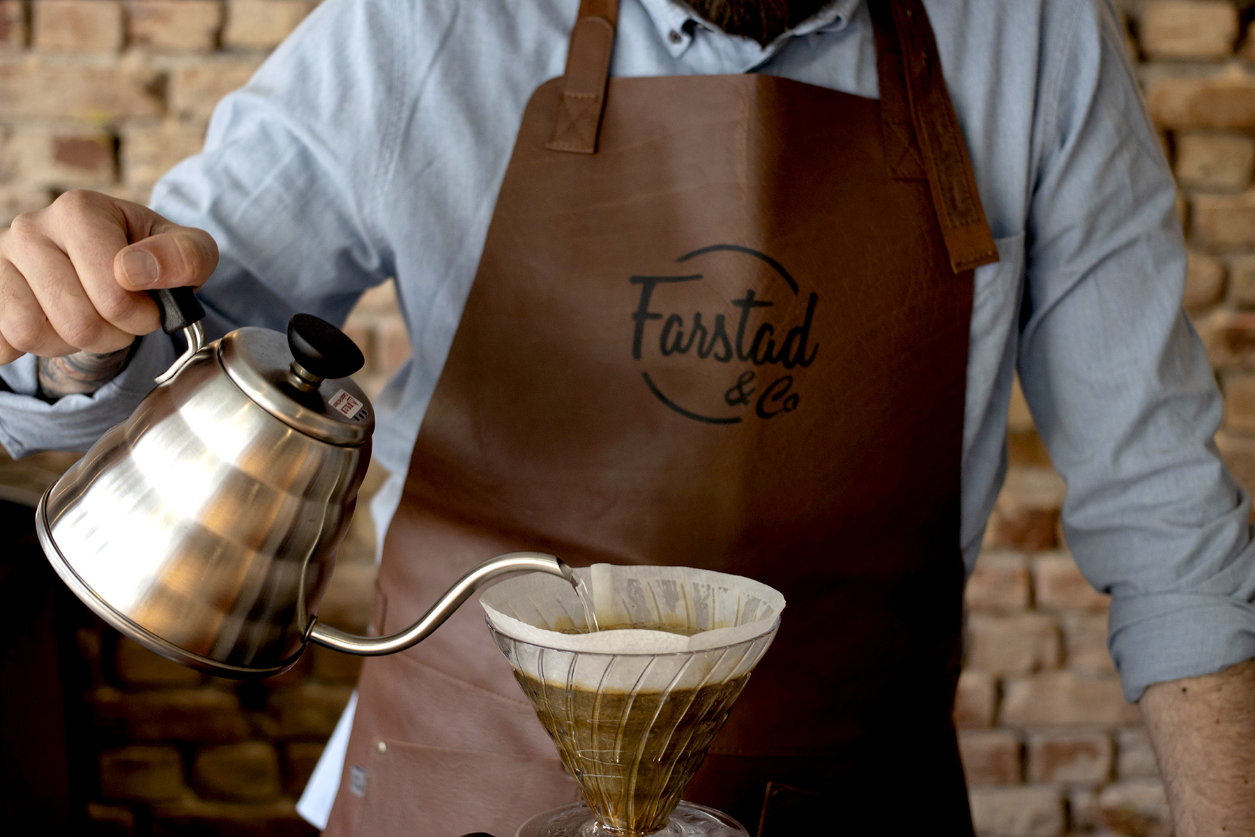 Man pouring hand brew coffee wearing a Farstad leather apron