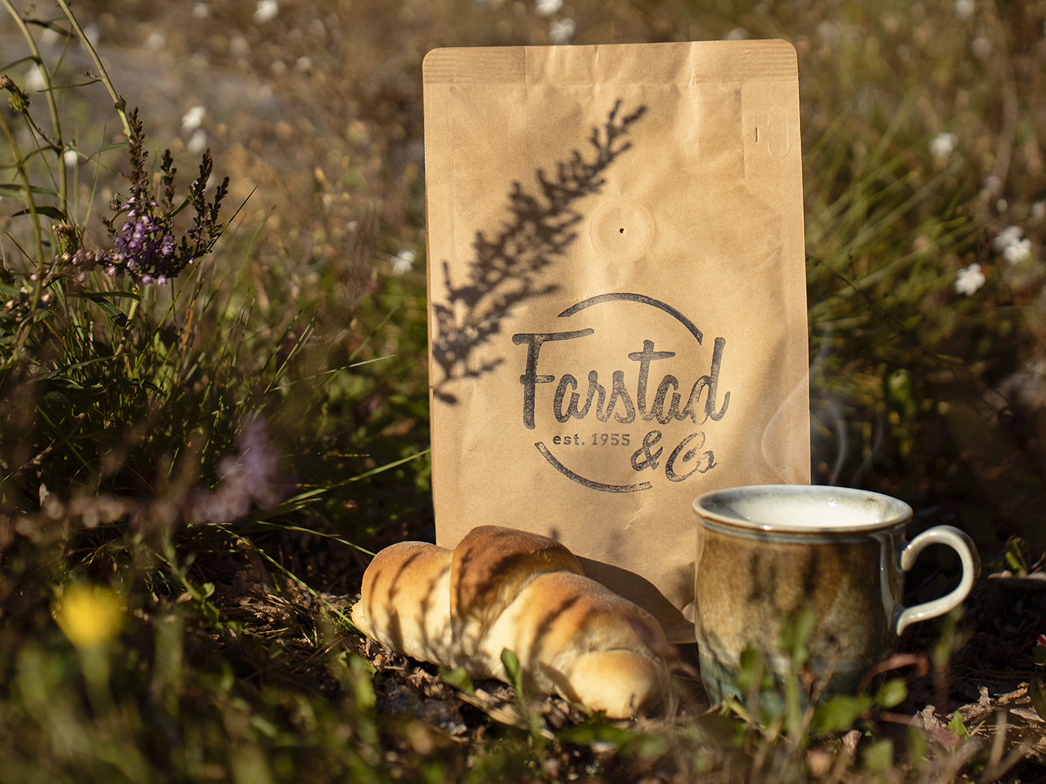 Photo of coffee bean bag in nature with a coffee mug and croissant