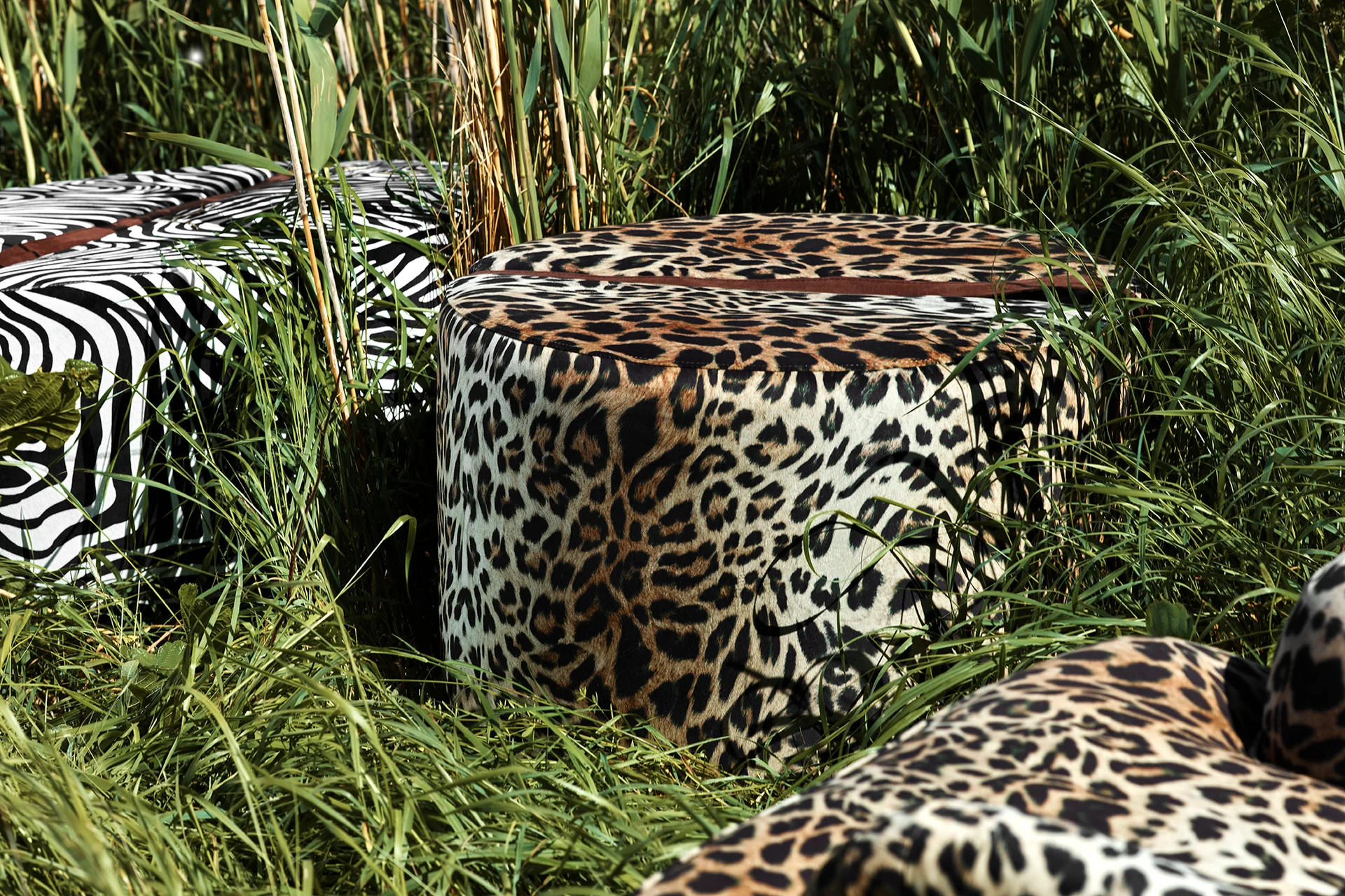 Stor, rund fotpall med leopardmönster i polyestersammet och med dekorativt band i anilinskinn.