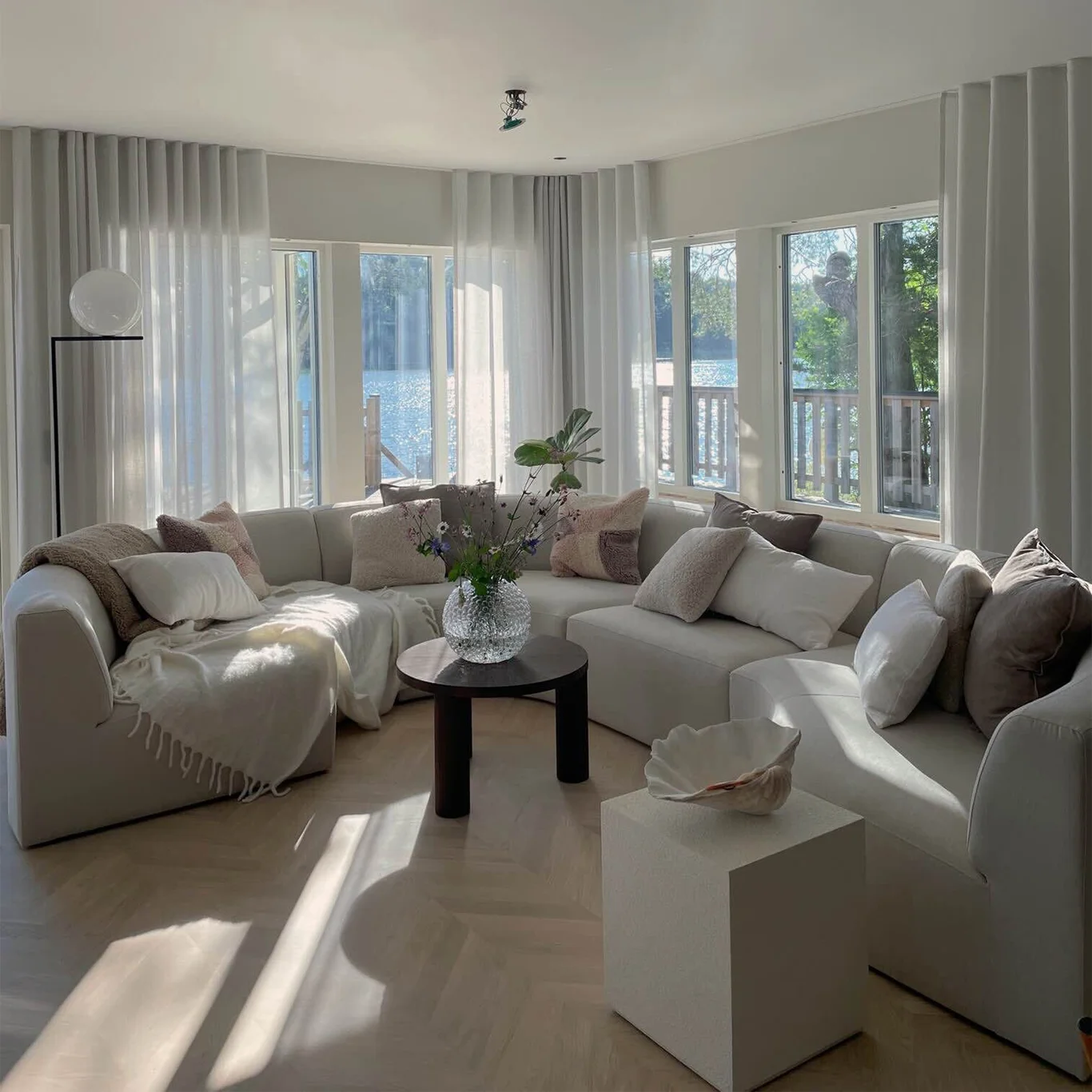 Stor, rund modulsoffa utan armstöd och med kallskum i sitsen, klädd i beige linneblandning.