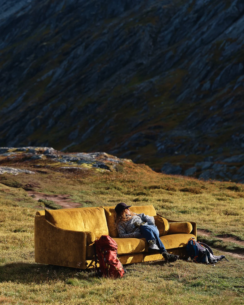 Antilopen guldig sammetssoffa med person sittandes i soffan.