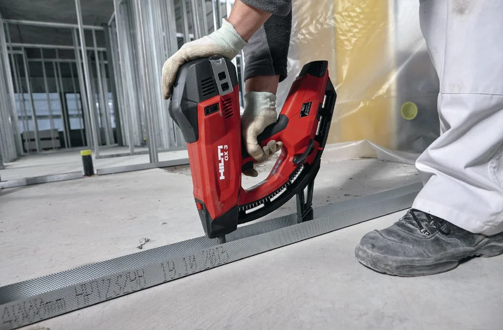 Installer fixing drywall track to concrete with the Hilti GX 3