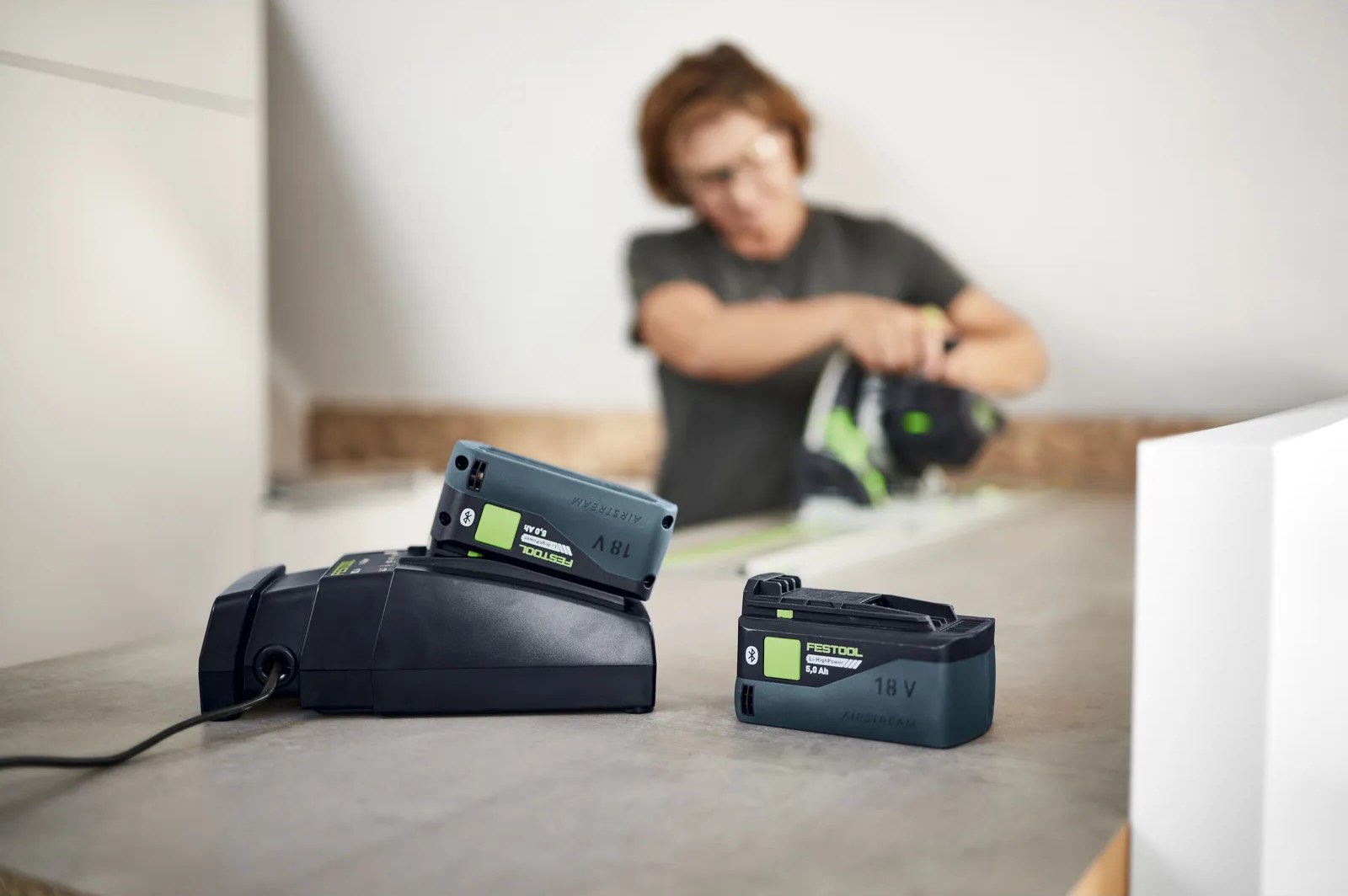 Battery packs on a charger with a user working in the background